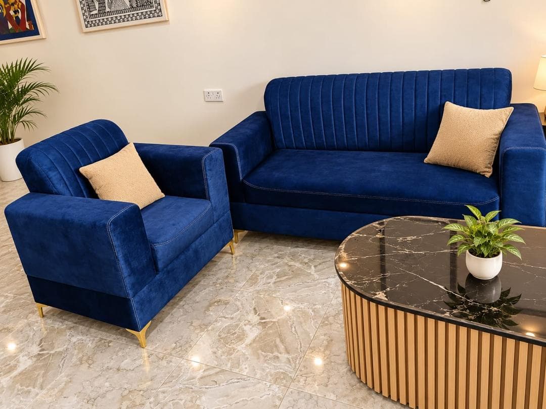 Blue velvet loveseat and armchair beside a marble-top coffee table